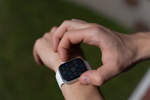 Detailed view of a hand interacting with a smartwatch outdoors.