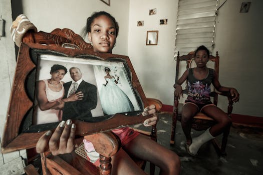 Two sisters sit indoors holding a family photo, capturing a moment of reminiscence.