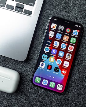 Flat lay of a smartphone, laptop, and earphones on a grey surface. Perfect for tech and gadget themes.